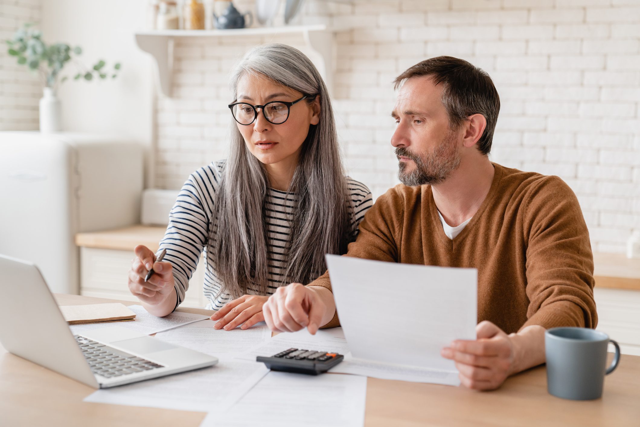 Couple reviewing finances with laptop and documents.