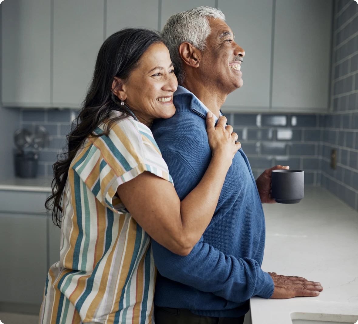 Smiling couple hugging in modern kitchen.